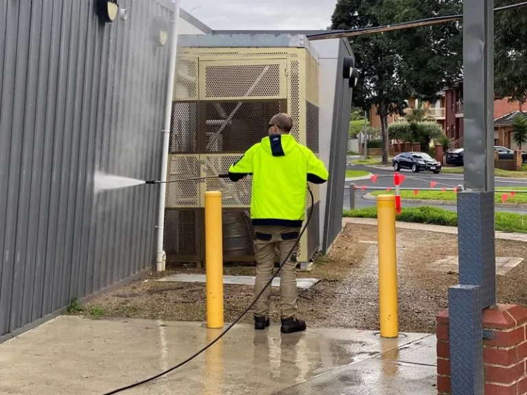 a man using a pressure washer cleaning a wall